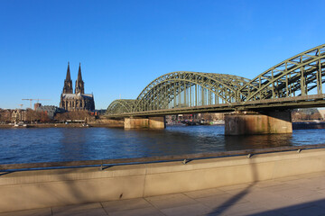 Obraz premium The Hohenzollern bridge over Rhine river on a sunny day. The Cologne Cathedral (Kolner Dom) in the city of Cologne, Germany. It is the largest Gothic church in northern Europe.