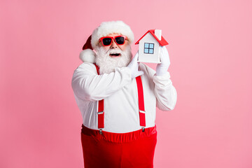 Portrait of his he nice attractive cheerful cheery glad fat Santa holding in hands house property insurance credit loan bank investment isolated over pink pastel color background