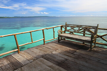 Fototapeta na wymiar Wooden chair on the dock at Ora Beach Resort in Seram Island, Central Maluku, Indonesia
