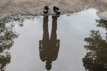 Shoes with shadow without the human / Reflection of shadow. Invisible man. Reflection of a man in a puddle.