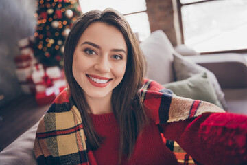 Photo of charming lady sit sofa make selfie shiny white smile wear blanket red sweater in decorated x-mas living room indoors