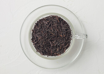 Organic black loose tea in clear glass cup on white background.
