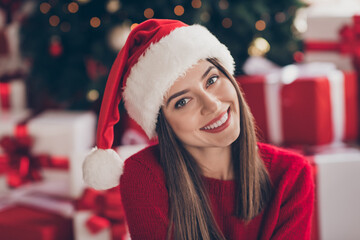 Photo of pretty young girl toothy beaming smile wear santa cap red sweater in decorated x-mas living room indoors