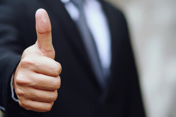 Businessman cool show hand giving thumb up as sign of Success.