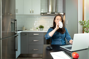 Bautifull women on a conforence call in home office in kitchen. Working from home. New normal...