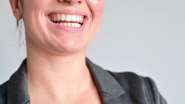 Close-up of a woman putting on transparent plastic retainers. The girl uses a device to straighten her teeth