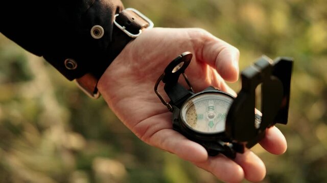 Man holds a compass in hand and looks for direction. Active lifestyle hiking enjoying vacation travel tourism adventure landscape nature. Travelling. Hiking. Orienteering on terrain.