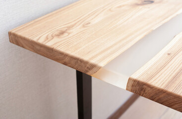 Wooden stylish table made of solid wood with epoxy resin on the background of the floor and wall. Close-up