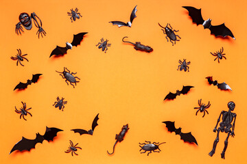 Halloween composition. Black skeletons, bats, spiders, flies, bugs and rats on orange background. Happy Halloween, trick or treat party concept. Flat lay, top view, copy space