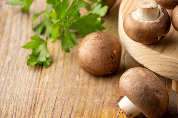 Close-up of portobello mushrooms and parsley on rustic wooden table, with selective focus, horizontal, with copy space