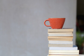 Stack of paperback books and a cup of coffee or tea. Selective focus.