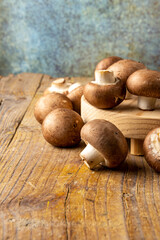 View of a group of portobello mushrooms on wooden board and rustic table, with selective focus, in vertical with copy space