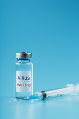 Ampoule and syringe with the vaccine against the Virus against diseases on a blue background.