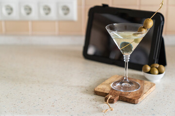 COvid-19 concept - quarantini drink martini via online communication with tablet, kitchen background