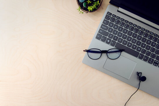 Business workspace. Online education concept. E-learning. Online training. Laptop, microphone and glasses for the computer on a wooden background, top view, copy space.