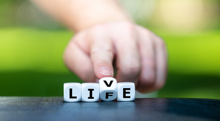 Live your life. Hand turns a dice and changes the word 