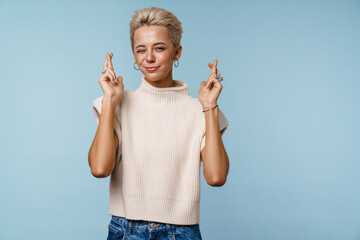 Beautiful girl winking and holding fingers crossed for good luck