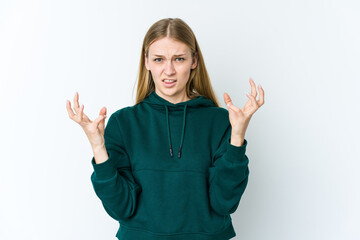 Young blonde woman isolated on white background upset screaming with tense hands.