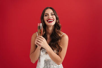 Charming happy girl in evening dress smiling and holding champagne glass