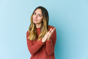 Young caucasian woman isolated on blue background feeling energetic and comfortable, rubbing hands...