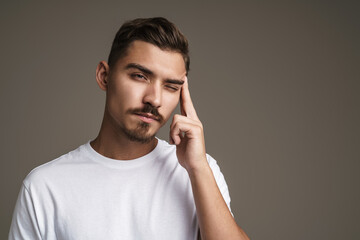 Image of unhappy unshaven guy with headache rubbing his temple