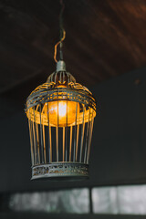 A beautiful metal lamp in the form of a cage with an electric lamp hanging as a decoration on the...