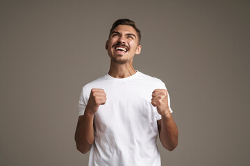 Image of excited unshaven guy making winner gesture and screaming