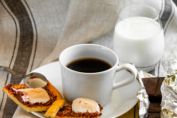 White cup of coffee with cookies, glass of milk and chocolate close-up. Morning breakfast.