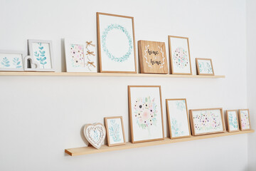 Watercolor flowers pictures on wall. Shelves with picture frames on white background. Creative...