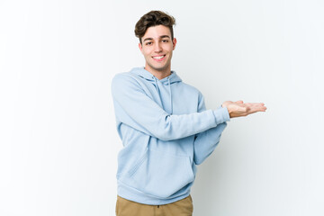 Young caucasian man isolated on white background holding a copy space on a palm.