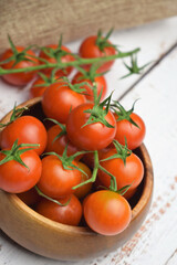 Natural presentation. Close up. Cherrys tomatoes on the branch on white wooden boards.