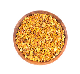 Flower pollen grains in wooden bowl, isolated on white background. Pile of bee pollen or perga. Top view.
