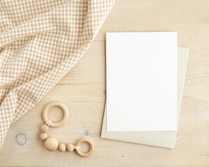 Flat lay composition with baby rattle, blanket and white empty card on rustic wooden background,...