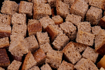 Pieces of roasted brown bread on a dark background. Close-up of delicious croutons.