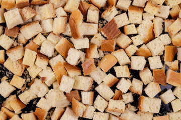 Pieces of roasted white bread on a dark background. Close-up of delicious croutons.