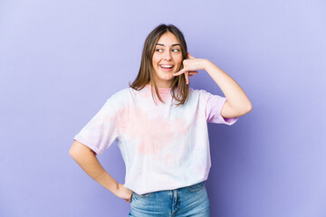 Young caucasian woman showing a mobile phone call gesture with fingers.