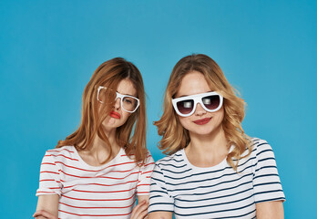 Obraz premium two cheerful girlfriends in striped t-shirts sunglasses hug friendship