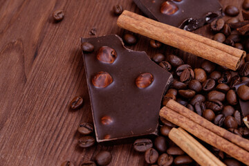 Chocolate bar with nuts on a wooden table with coffee beans and spices. Roasted coffee beans and...