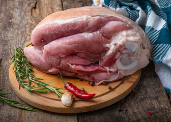 Raw pork shank with rosemary and pepper on wooden background. Close-up. Pork shank before cooking.
