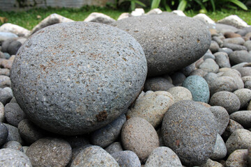 Fototapeta na wymiar Big stones among smaller pebbles, in the garden