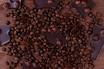 Chocolate bar with nuts on a wooden table with coffee beans and spices. Roasted coffee beans and anise stars. Top view.