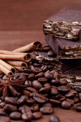 Wafer bars covered with chocolate on a dark wooden background with coffee beans, cinnamon sticks...