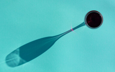 wineglass of red wine with a shadow on a aquamarine background top view flat lay, minimal art