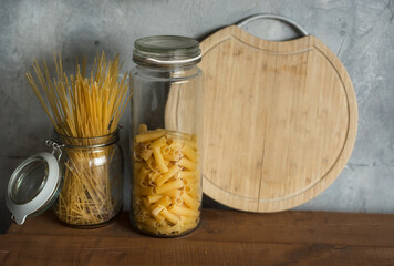 Close-up of glass jars with pasta on the background of home interior.