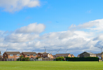 Two-story houses near a football field on a sunny day.