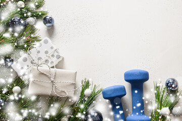 Christmas composition with blue dumbbells, gift, fir branches on white. Copy space. Xmas greeting card.