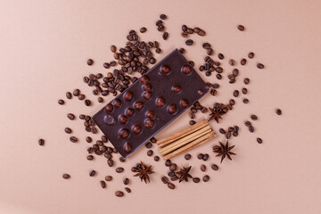 Chocolate bar with nuts on the beige background with coffee beans and spices. Roasted coffee beans,...