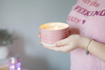 A girl in a pink T-shirt holds an aroma candle in her hands. Comfort in home.