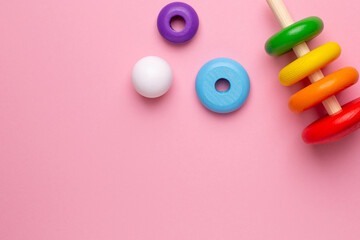 Colorful children's wooden pyramid on a pink background, toy for toddlers and babies