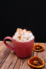 Pumpkin spice latte with cinnamon and white pumpkins on wooden and black background. Harvest season and cozy pumpkin food backdrop. Space for writing. Hot chocolate with marshmallow. 